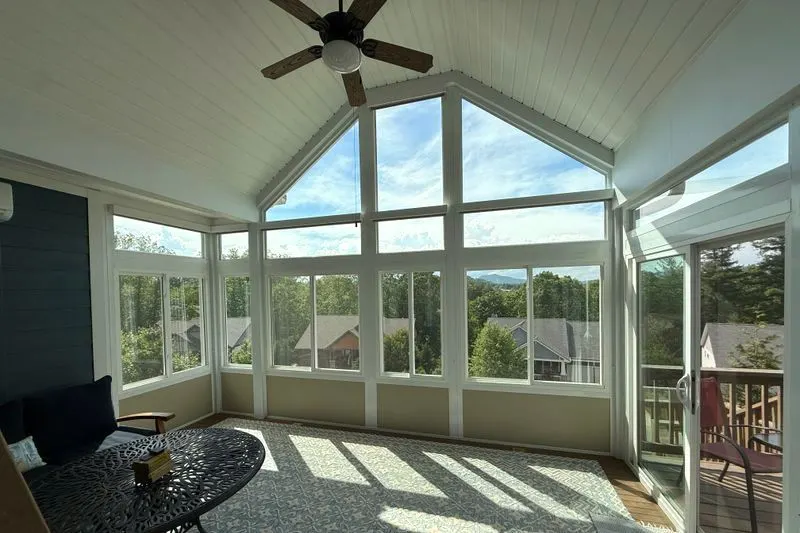 Motorized roller shades on a sunroom wall of windows