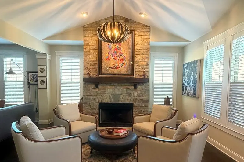 Living room with plantation shutters on every window around a stone fireplace